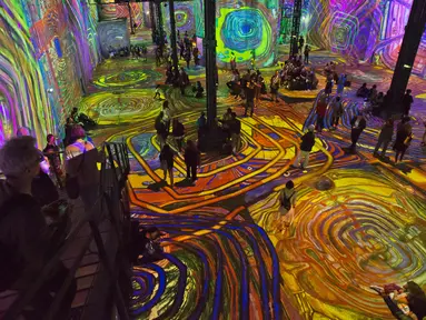 Pengunjung menikmati karya pelukis Austria, Friendensreich Hundertwasser di galeri l'Atelier des Lumieres di Paris, Prancis (24/4). Dalam pameran ini pengunjung bisa menikmati lukisan dalam bentuk digital. (AP/Michel Euler)