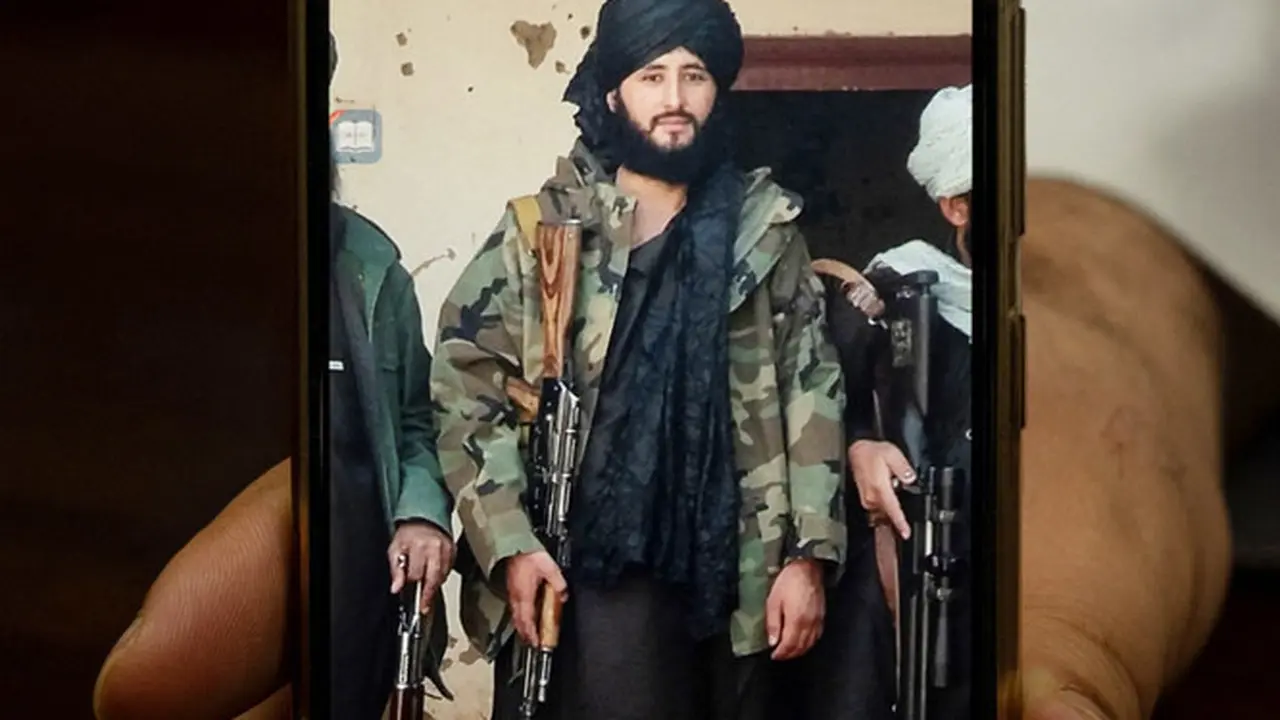 Foto yang diambil pada 18 Januari 2022 ini menunjukkan Wali Kota Maymana Damullah Mohibullah Mowaffaq memegang ponselnya dengan foto dirinya saat menjadi pejuang Taliban, di Maymana. (AFP)