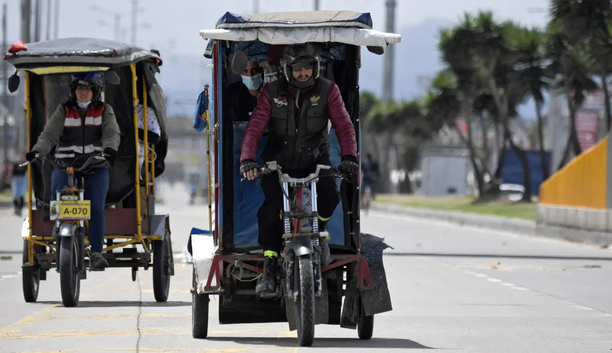 Orang-orang menggunakan bicitaxis setelah penghancuran beberapa stasiun layanan publik di Bogota (24/5/2021). Secara resmi, 43 orang tewas dalam bentrokan sejak protes menentang reformasi pajak yang diusulkan yang telah ditarik. (AFP/ Raul Arboleda)