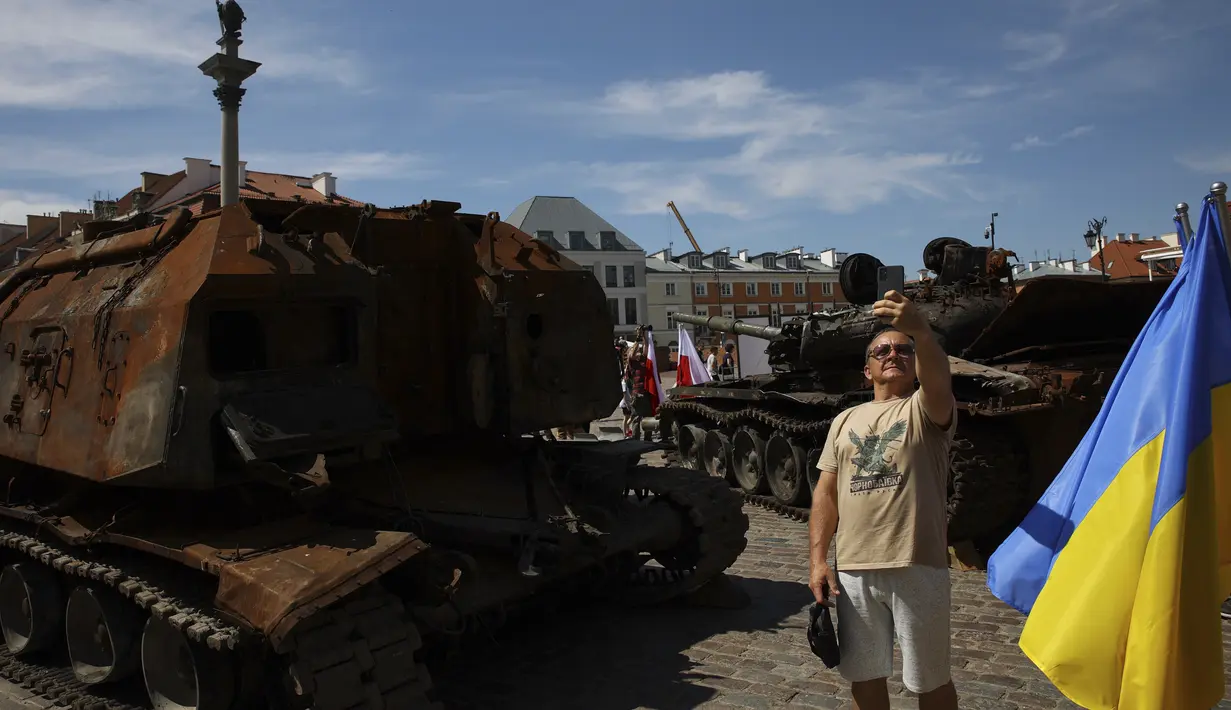 Seorang pria berselfie di dekat tank Rusia yang rusak dan terbakar di Castle Square, di Warsawa, Polandia (27/6/2022). Pihak berwenang Ukraina mengumumkan bahwa ada rencana untuk pameran serupa di ibu kota Eropa lainnya seperti Berlin, Paris, Madrid dan Lisbon. (Foto AP/Michal Dyjuk)