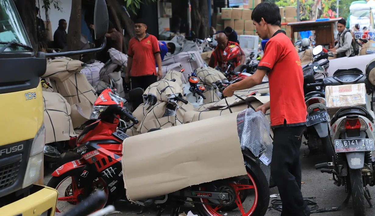 Pekerja membungkus sepeda motor yang akan dikirim di Stasiun Pasar Senen, Jakarta, Selasa (5/6). Jasa pengiriman motor ke daerah meningkat dua kali lipat jelang arus mudik dan Hari Raya Idulfitri 2018. (Liputan6.com/Arya Manggala)