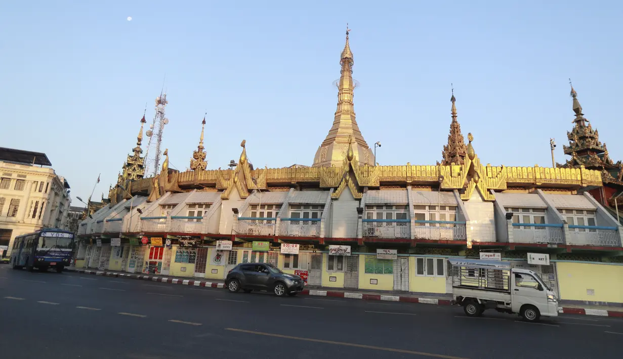 Kendaraan melewati Pagoda Sule di Yangon saat militer Myanmar merebut kekuasaan pemerintah, Senin (1/2/2021). Rekaman video yang disiarkan di televisi milik militer mengatakan kekuasaan telah diserahkan kepada panglima tertinggi militer Myanmar, Jenderal Senior Min Aung Hlaing. (AP Photo/Thein Zaw)