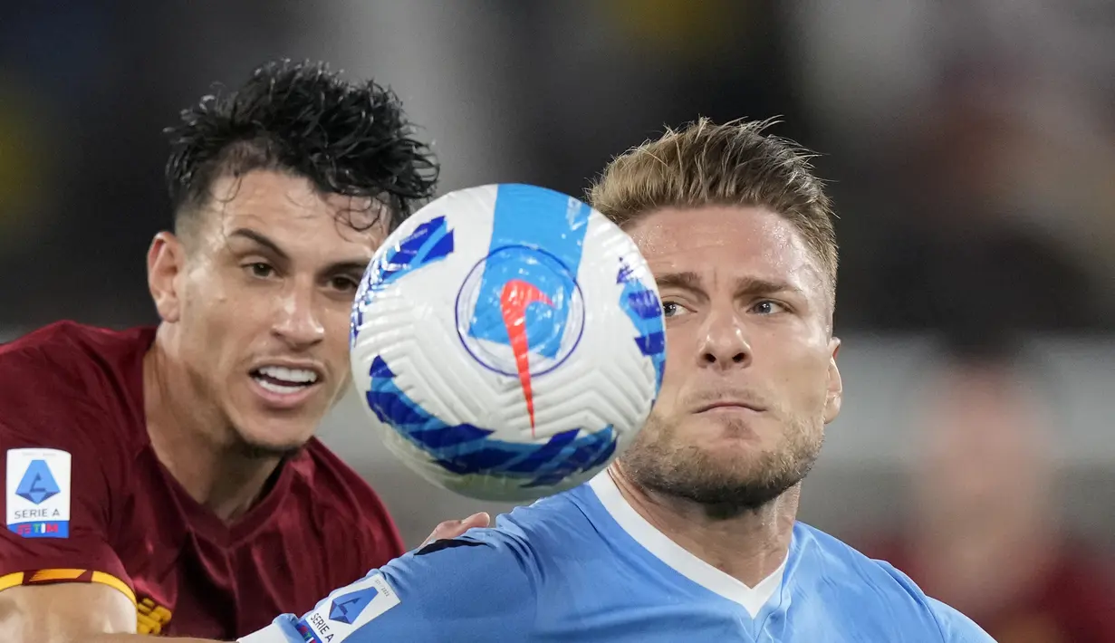 Penyerang Lazio, Ciro Immobile berebut bola dengan pemain AS Roma, Roger Ibanez pada pertandingan lanjutan Liga Serie A Italia di Stadion Olimpiade Roma, Senin (27/9/2021). Dengan kemenangan ini Lazio kini naik ke posisi enam dengan 11 poin dari enam laga. (AP  Photo/Andrew Medichini)