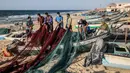 Nelayan Palestina yang mengenakan masker karena pandemi virus corona COVID-19 menyiapkan jala ikan di sepanjang pantai Laut Mediterania, Rafah, Jalur Gaza, Rabu (2/9/2020). (SAID KHATIB/AFP)
