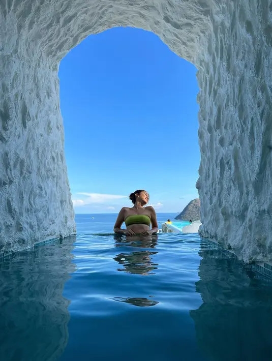 Momen Tyna bersantai di kolam renang estetik. Foto ala candid, Tyna masih dengan outfit bikini two piece model bandeau warna hijau. (Instagram/tynadwijayanti)