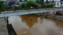 Seorang anak nekat melompat dari jembatan ke Kali Ciliwung Kalibata, Jakarta, Selasa (25/2/2020). Kali Ciliwung meluap usai hujan deras mengguyur Jakarta dan sekitarnya pada kemarin malam. (merdeka.com/magang/Muhammad Fayyadh)