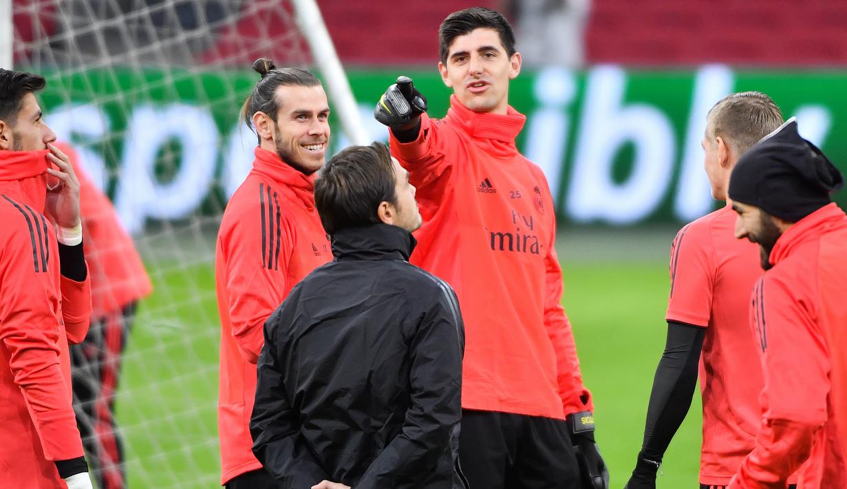 Kiper Real Madrid, Thibaut Courtois, berbincang dengan Gareth Bale saat latihan jelang laga Liga Champions 2019 di Johan Cruijff Arena, Selasa (12/2). Real Madrid akan berhadapan dengan Ajax Amsterdam. (AFP/Emmanuel Dunand)
