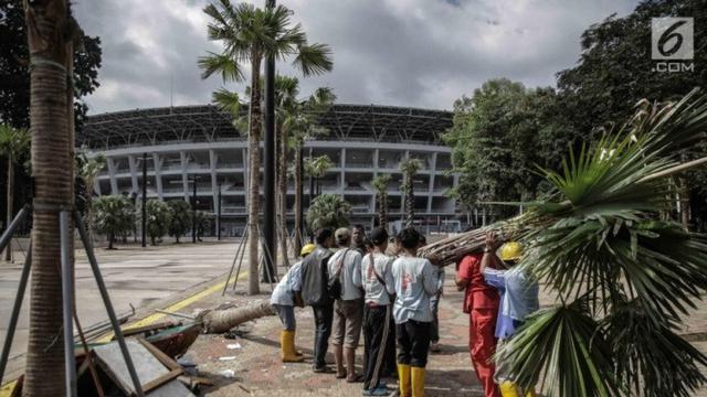 Petugas menumbangkan pohon yang rusak akibat ulah oknum suporter yang menyaksikan laga Final Piala Presiden 2018 di Stadion Utama GBK, Jakarta, Minggu (18/2) (Liputan6.com/Faizal Fanani)