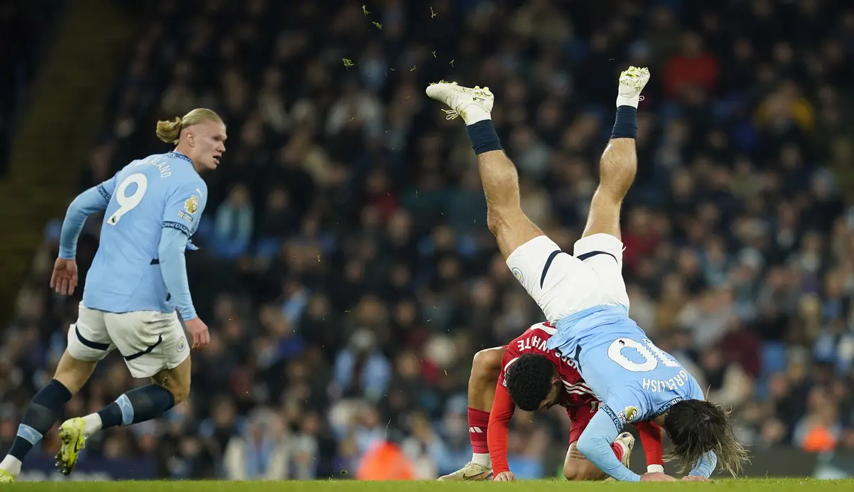 <p>Pemain Manchester City, Jack Grealish (kanan) terjatuh saat berebut bola dengan pemain Nottingham Forest, Morgan Gibbs-White pada laga lanjutan Liga Inggris 2024/2025 di Etihad Stadium, Manchester, Inggris, Kamis (05/12/2024). (AP Photo/Martin Rickett)</p>