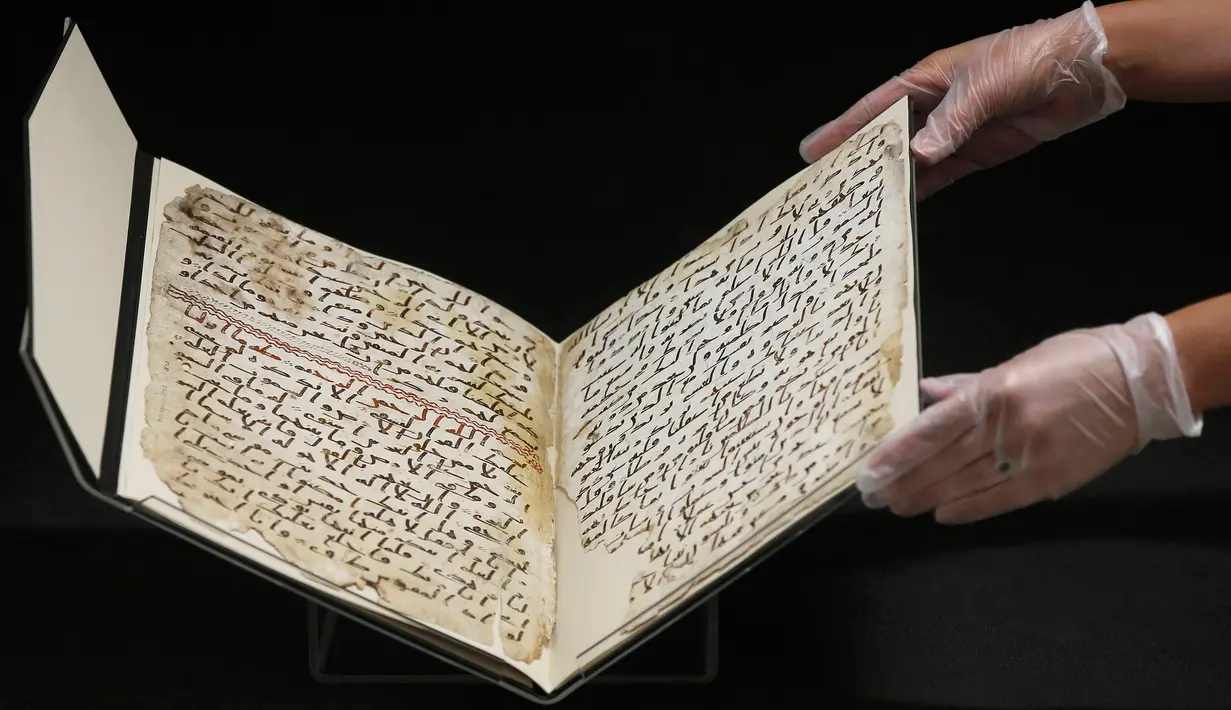 Ahli Manuskrip memperlihatkan penggalan naskah Al-Quran tertua di dunia yang ditemukan di Universitas Birmingham, Inggris, Rabu (22/7/2015). Penanggalan radiokarbon menunjukkan manuskrip itu berusia setidaknya 1.370 tahun. (REUTERS/Peter Nicholls)