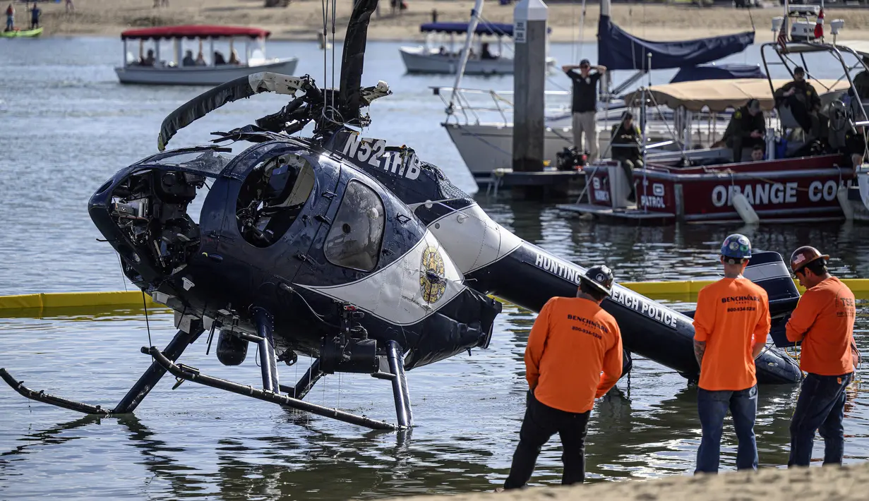 Sebuah derek digunakan untuk mengangkat helikopter Polisi Pantai Huntington di Pantai Newport, California (20/2/2022). Pihak berwenang sedang menyelidiki penyebab kecelakaan helikopter polisi di sepanjang pantai California Selatan tersebut. (Mindy Schauer/The Orange County Register via AP)