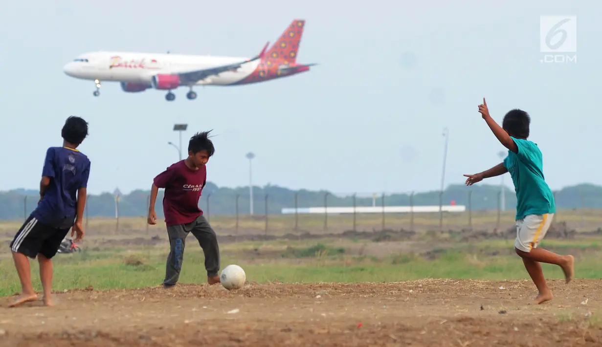Anak-anak bermain bola di kawasan proyek perluasan landasan pacu atau Runway 3A Bandara Soekarno-Hatta (Soetta), Rawa Bokor, Tangerang, Banten, Selasa (2/7/2019). Mereka memanfaatkan lahan kosong yang belum dikerjakan pihak kontraktor untuk bermain bola. (merdeka.com/Arie Basuki)
