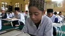 Santri yang masih berusia belasan tahun membaca Al Quran bersama-sama (tadarus) dalam rangka mengkhatamkan Qur'an dengan menerapkan jaga jarak pada Masjid Daarul Qu'ran  Pesantren Al Kautsar, Cibinong, Bogor, Jawa Barat, Minggu (10/04/2022). (merdeka.com/Arie Basuki)