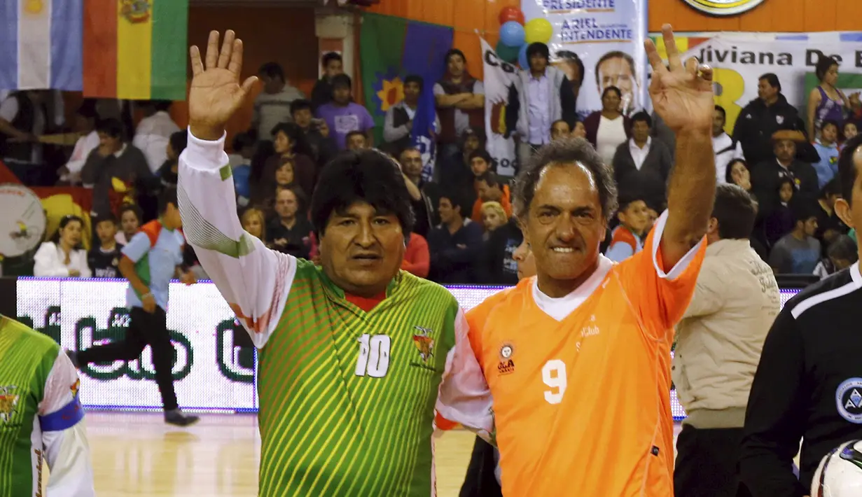 Evo Morales (kiri) dan Daniel Scioli, gubernur provinsi Buenos Aires dan calon presiden Argentina dari Victory menyapa penonton sebelum memainkan pertandingan sepak bola di Benavidez, Buenos Aires, Argentina (17/9/2015). (REUTERS/Marcos Brindicci)
