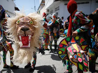 Sejumlah orang menari sambil mengenakan kostum dan topeng saat perayaan tradisional di Naiguata, Venezuela (31/5). Sejumlah orang kerasukan dan menari selama festival yang dikenal Dancing Devils ini di Naiguata. (AP/Arian Cubillos)
