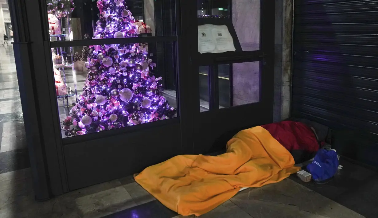 Tunawisma tidur di lantai di luar restoran di Milan, Italia utara, 27 November 2020. Dinas Pertanian di Italia mengatakan pandemi COVID-19 telah menciptakan 300.000 yang disebut "orang miskin baru,” berdasarkan survei dari asosiasi amal yang beroperasi di Lombardy tersebut. (AP Photo/Luca Bruno)