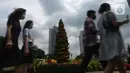 Warga DKI Jakarta melintas di dekat hiasan pohon Natal 2021 di Bundaran HI, Jakarta, Sabtu (25/12/2021). Libur Natal 2021 dimanfaatkan sebagian warga berfoto berlatar pohon Natal yang telah dihias atau berjalan-jalan ke mal untuk mengisi waktu berlibur bersama. (merdeka.com/Imam Buhori)