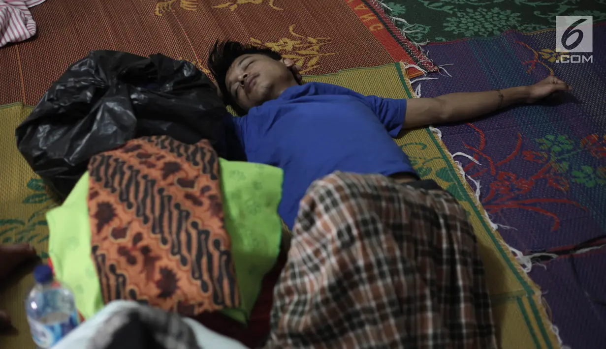 Seorang pengungsi pria yang rumahnya terendam banjir tertidur saat mengungsi di Kelurahan Kampung Melayu, Jatinegara, Jakarta Timur, Rabu (7/2). Warga tidur hanya beralaskan tikar dan berselimut kain tipis. (Liputan6.com/Arya Manggala)