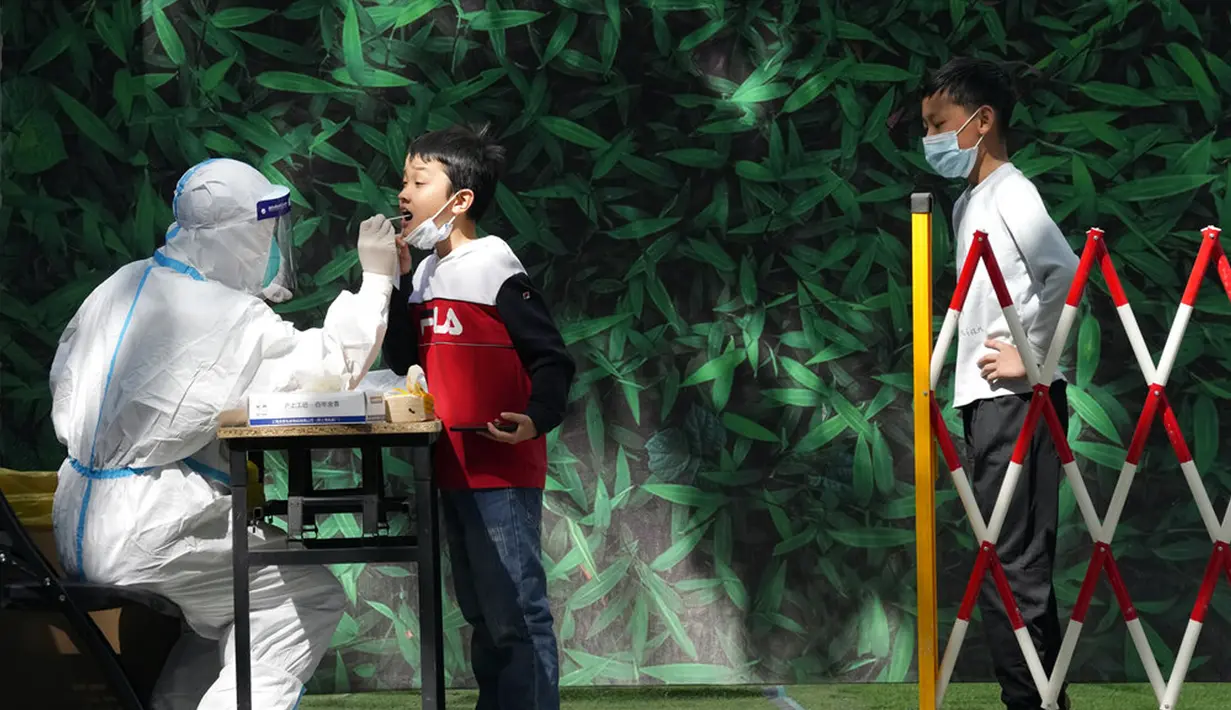 <p>Seorang anak diambil sampelnya saat tes COVID-19 massal di Beijing, China, Selasa (3/5/2022). China telah berpegang teguh pada pendekatan ketat 'Nol COVID' yang membatasi perjalanan, menguji massal seluruh kota, dan mendirikan fasilitas sementara yang luas untuk mencoba mengisolasi setiap orang yang terinfeksi. (AP Photo/Ng Han Guan)</p>