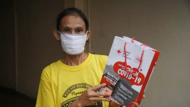 PMI membantu masyarakat menggunakan masker.