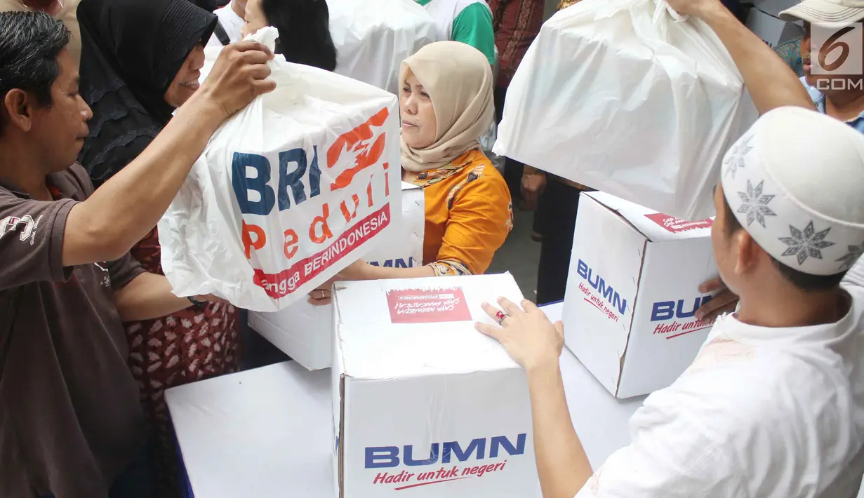 Warga menerima paket sembako Ramadan dari BUMN di di Jalan Rawa Bebek, Kecamatan Penjaringan, Jakarta Utara, Selasa (13/6). Setiap warga sudah dibekali kupon yang diberikan pihak BRI sehari sebelum pembagian. (Liputan6.com/Angga Yuniar)