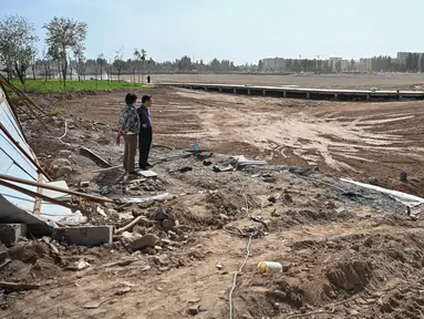 Gambar pada 12 September 2019 menunjukkan orang-orang berdiri dekat pemakaman etnis Uighur di Shayar, wilayah Xinjiang. China menghancurkan banyak area pemakaman keluarga Uighur yang telah menjadi tempat peristirahatan terakhir etnis minoritas itu dari generasi ke generasi. (HECTOR RETAMAL/AFP)