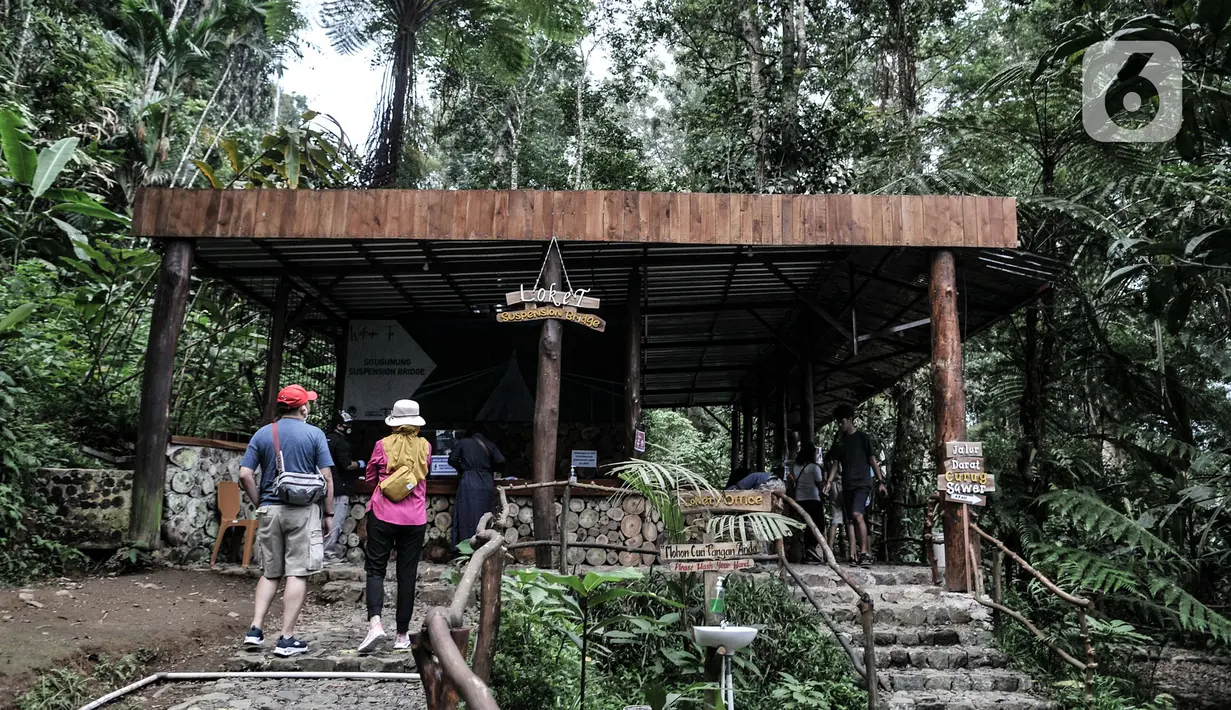 Pengunjung antre dengan berjaga jarak saat membeli tiket masuk wisata Jembatan Gantung (Suspension Bridge) Situ Gunung, Sukabumi, Jawa Barat, Minggu (20/9/2020).  Jumlah wisatawan yang berkunjung ke Jembatan Gantung terpanjang se-Asia Tenggara tersebut menurun drastis. (merdeka.com/Iqbal S. Nugroho)