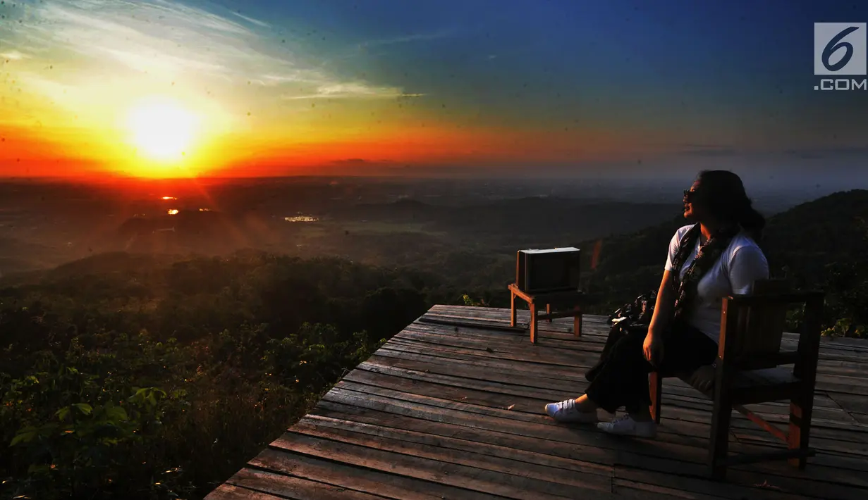 Seorang wisatawan menunggu matahari terbenam di Puncak Watu Goyang usai berkeliling dengan jip di Desa Wisata Kaki Langit Mangunan, Bantul, Yogyakarta (4/5). (Merdeka.com/Arie Basuki)