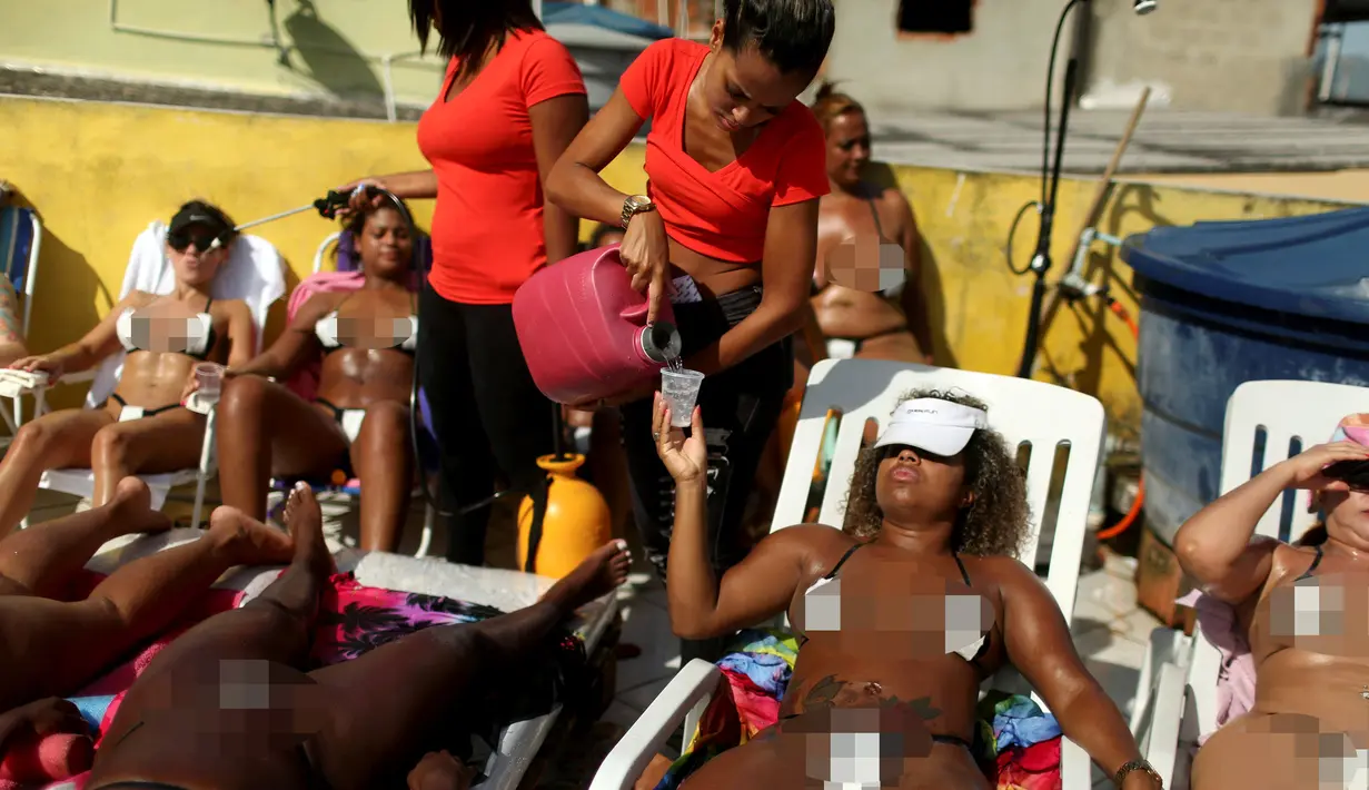 Seorang pekerja dari spa Erika Bronze menyajikan secangkir air kepada seorang pengunjung saat berjemur di Rio de Janeiro, Brasil (22/11). Tarif untuk spa dan berjemur ditempat ini sekitar 20 dolar untuk selama tiga setengah jam. (Reuters/Pilar Olivares)