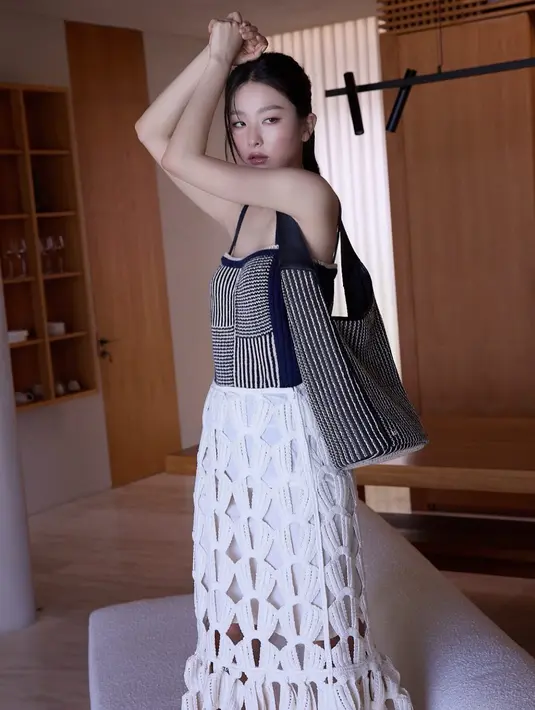 Anggota Red Velvet ini juga mengenakan atasan hitam sleeveless bergaris serasi dengan totebagnya. Dipadukan rok panjang hitam. [@hi_sseulgi]