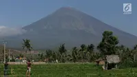 Dua orang pria mengambil gambar Gunung Agung Karangasem, Bali, Rabu (27/9). Sebagian warga yang tinggal di kawasan rawan bencana di lereng timur laut Gunung Agung masih belum mengungsi meski gunung berstatus awas. (Liputan6.com/Gempur M Surya)