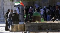 Seorang pengunjuk rasa Palestina mengibarkan bendera Palestina saat bentrokan dengan pasukan keamanan Israel di Kompleks Masjid Al Aqsa, Kota Tua Yerusalem, 15 April 2022. (AP Photo/Mahmoud Illean)