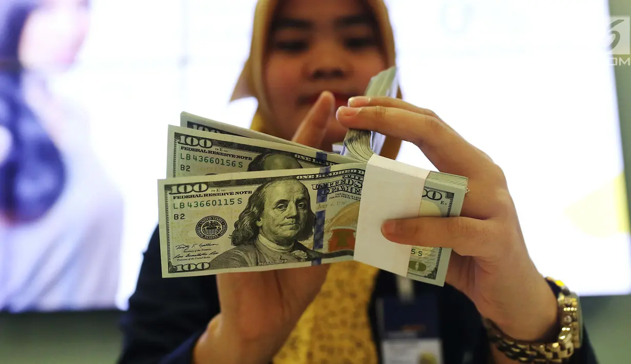 Pekerja bank menghitung uang dollar AS di Jakarta, Jumat (20/10). Pagi ini, Rupiah dibuka di Rp 13.509 per USD atau menguat tipis dibanding penutupan perdagangan sebelumnya di Rp 13.515 per USD. (Liputan6.com/Angga Yuniar)