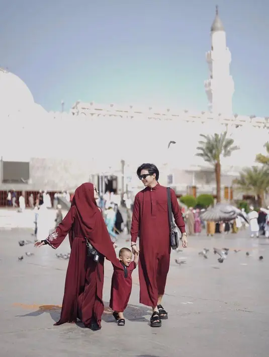 Bergandengan tangan bersama Arshaka, keluarga kecil ini tampil kompak mengenakan busana warna merah. Dinda terlihat mengenakan gamis dan hijab merah, sementara Rey dan putra kecilnya kembaran pakai thawb. (Instagram/dindahw).