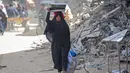 Seorang wanita Palestina membawa barang-barangnya di Khan Yunis di Jalur Gaza selatan pada 6 Maret 2024. Badan Bantuan dan Pekerjaan PBB (UNRWA) menyatakan bahwa rata-rata 63 perempuan terbunuh di Gaza setiap harinya, dan sekitar 37 diantaranya adalah ibu. (Foto: AFP)