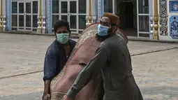 Umat Muslim melepas karpet sajadah dari aula utama masjid menyusul pembatasan baru pemerintah baru menjelang Ramadan di Rawalpindi, Pakistan, Senin (5/4/2021). Sesuai pedoman, karpet atau permadani tidak akan digunakan di masjid dan salat akan dilakukan di lantai tanpa karpet. (Aamir QURESHI/AFP)