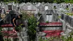 Warga keturunan Tionghoa membersihkan makam keluarga saat Festival Cheng Beng di Pemakaman Tionghoa di Japakeh, Banda Aceh, Aceh, Minggu (26/3/2023). (CHAIDEER MAHYUDDIN/AFP)
