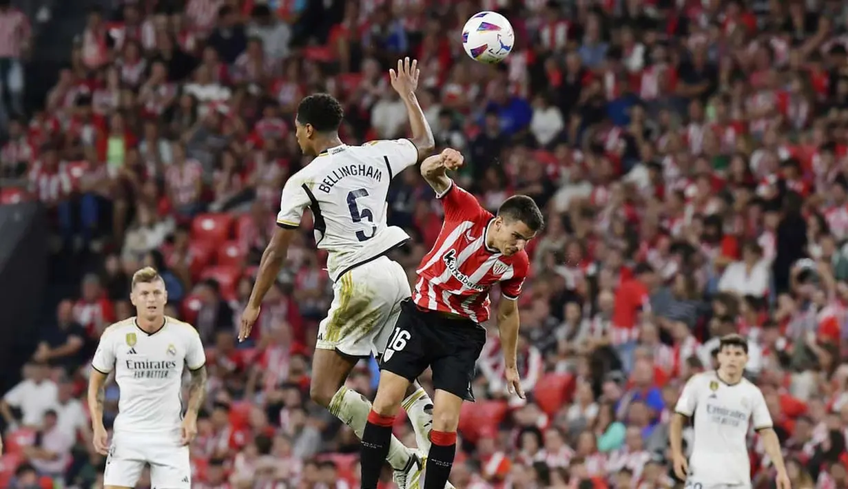Pemain Real Madrid, Jude Bellingham, berebut bola dengan pemain Athletic Bilbao, Inigo Ruiz, pada laga pekan ke-1 La Liga 2023/2024 di Stadion San Mames, Minggu (13/8/2023). Los Blancos menang dengan skor 2-0. (AP Photo/Alvaro Barrientos)