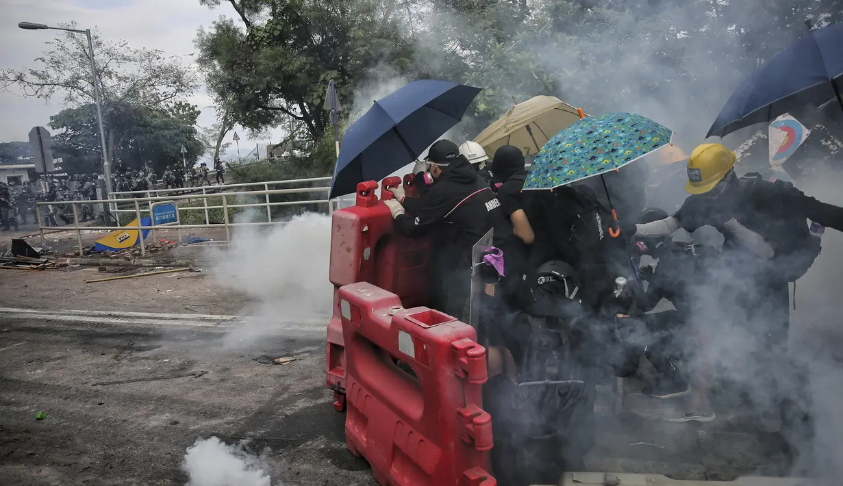 Sejumlah siswa menggunakan payung berlindung di belakang barikade selama bentrokan dengan polisi di Universitas China di Hong Kong (12/11/2019). Ketapel hingga panahan digunakan para demonstran Hong Kong sebagai senjata saat unjuk rasa yang telah berlangsung selama lima bulan. (Steve Leung/HK01 via