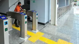 Petugas membersihkan mesin gate karcis elektronik di Stasiun Matraman, Jakarta, Senin (13/6/2022). Sebagai persiapan pengoperasian Stasiun Matraman, telah dilakukan uji coba perjalanan KRL, uji coba sistem persinyalan, serta uji coba prasarana-prasarana operasional perjalanan kereta api lainnya. (Liputan6.com/Herman Zakharia)