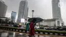 <p>Warga menggunakan payung melintas di kawasan Bundaran Hi, Jakarta, Sabtu (13/11/2021). Badan Meteorologi Klimatologi dan Geofisika (BMKG) melansir peringatan terbaru yang berlaku 7-9 November 2021 soal peringatan cuaca ekstrem imbas dari La Nina. (Liputan6.com/Faizal Fanani)</p>