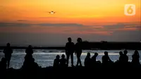 Wisatawan lokal beraktivitas di pantai yang surut dengan latar belakang pesawat di Pantai Kelan, Badung, Bali, Sabtu (22/4/2023). (merdeka.com/Arie Basuki)