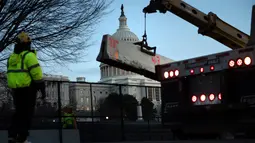 Para pekerja memperkuat pagar pengendali massa di sekitar Capitol Hill AS, Washington D.C, dengan penghalang beton sehari setelah peristiwa kericuhan Kamis (7/1/2021). Peristiwa penyerbuan di gedung Capitol Hill AS dilakukan oleh massa pendukung Donald Trump pada 6 Januari. (Brendan Smialowski/AFP)