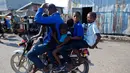 Pengendara motor membawa lima penumpang melewati area Cite Soleil di Port-au-Prince, Haiti (17/3). Daerah ini umumnya dianggap sebagai salah satu daerah termiskin dan paling berbahaya di Belahan Barat. (AP Photo/Dieu Nalio Chery)