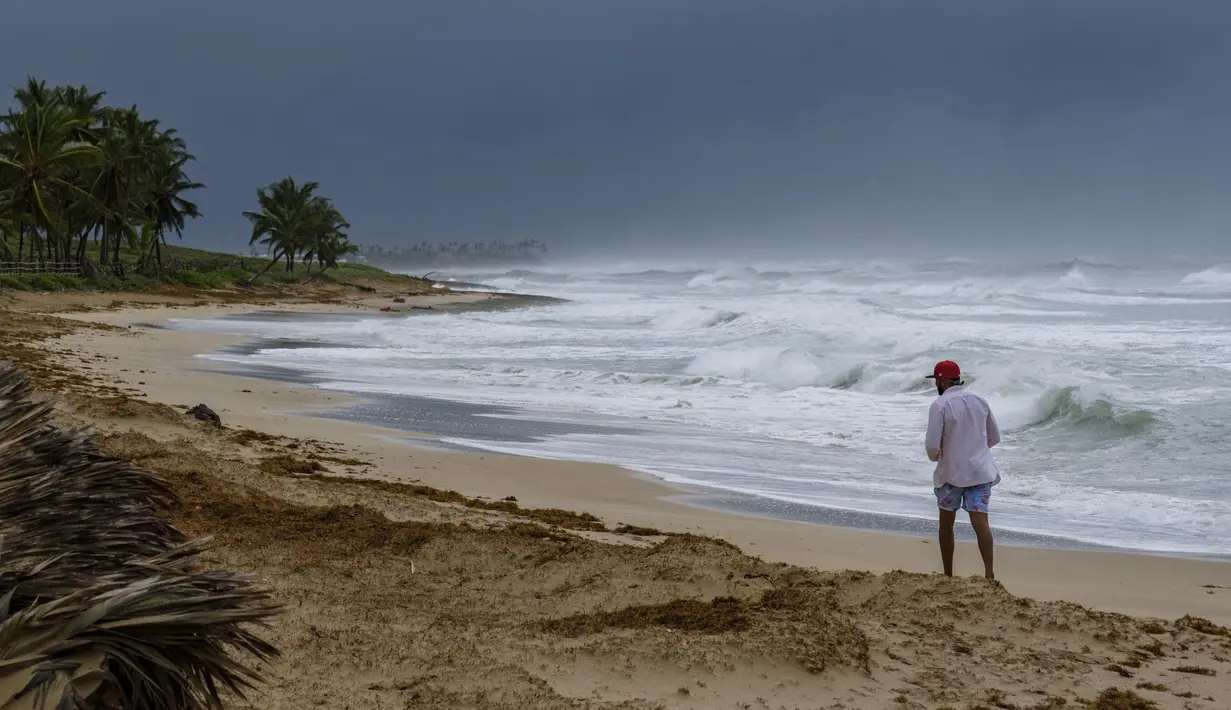 Seorang pria berjalan di pantai di sebelah ombak yang diterjang Badai Fiona di Punta Cana, Republik Dominika (19/9/2022). Presiden Republik Dominika, Luis Abinader berencana mengumumkan keadaan bencana di provinsi La Altagracia, tempat resor terkenal Punta Cana, El Seibo dan Walikota Hato. (AP Photo/Ricardo Hernandez)
