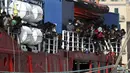 Migran berada di atas Kapal Sea Eye 4 saat tiba di Trapani, Sisilia, Italia, Minggu (7/11/2021). Kapal kemanusiaan Jerman diberikan izin oleh otoritas Italia setelah berhari-hari menunggu di Laut Mediterania. (Alberto Lo Bianco/LaPresse via AP)