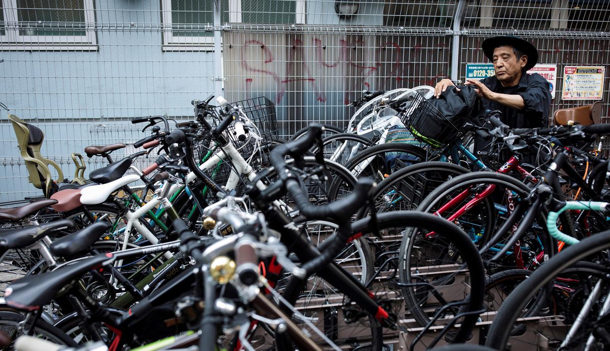 Seorang pria mengambil sepedanya dari parkiran di lingkungan Shibuya di Tokyo, Jepang (23/5/2019). Pada tahun 2008, distrik kota ini mempunyai populasi sekitar 208.371 jiwa dan kepadatan penduduk 13.337,13 orang per km². (AFP Photo/Behrouz Mehri)