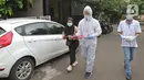 Petugas KPPS menggunakan hazmat sebelum menuju rumah pemilih di kawasan Depok, Rabu (9/12/2020). Petugas jemput bola atau mengambil suara dari warga yang diduga terpapar COVID-19 atau sedang menjalani isolasi mandiri di salah satu perumahan dalam Pilkada Depok 2020. (Liputan6.com/Herman Zakharia)