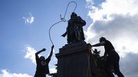 Mike Forcia (kiri) dan seorang pria mengikatkan tali pada leher patung Christopher Columbus saat sekelompok massa merobohkannya di Minnesota State Capitol, St. Paul, Minnesota, Amerika Serikat, Rabu (10/6/2020). (Evan Frost/Minnesota Public Radio via AP)