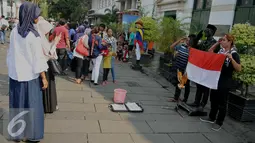 Pengunjung berpose dengan manusia patung saat mengunjungi Kota Tua, Jakarta, Jumat (8/7). Kota Tua menjadi salah satu pilihan masyarakat Jakarta ataupun luar Jakarta, untuk mengisi libur lebaran. (Liputan6.com/Gempur M Surya)